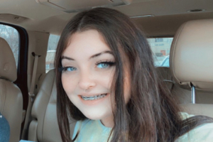 Chelsey Updike-In Car-Featured-Image-450x300 A photographic image of Chelsey Updike smiling into the camera while sitting in the driver's seat of a car.