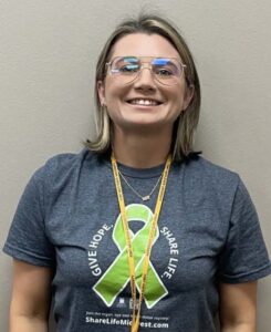 A woman wearing glasses, smiling for the camera.