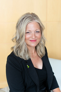 Be ALL IN-Web-200x300-Jami Gleason Headshot of Jami Gleason, smiling, wearing a black shirt and black blazer