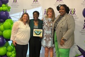 Four women pose with a framed butterfly award.
